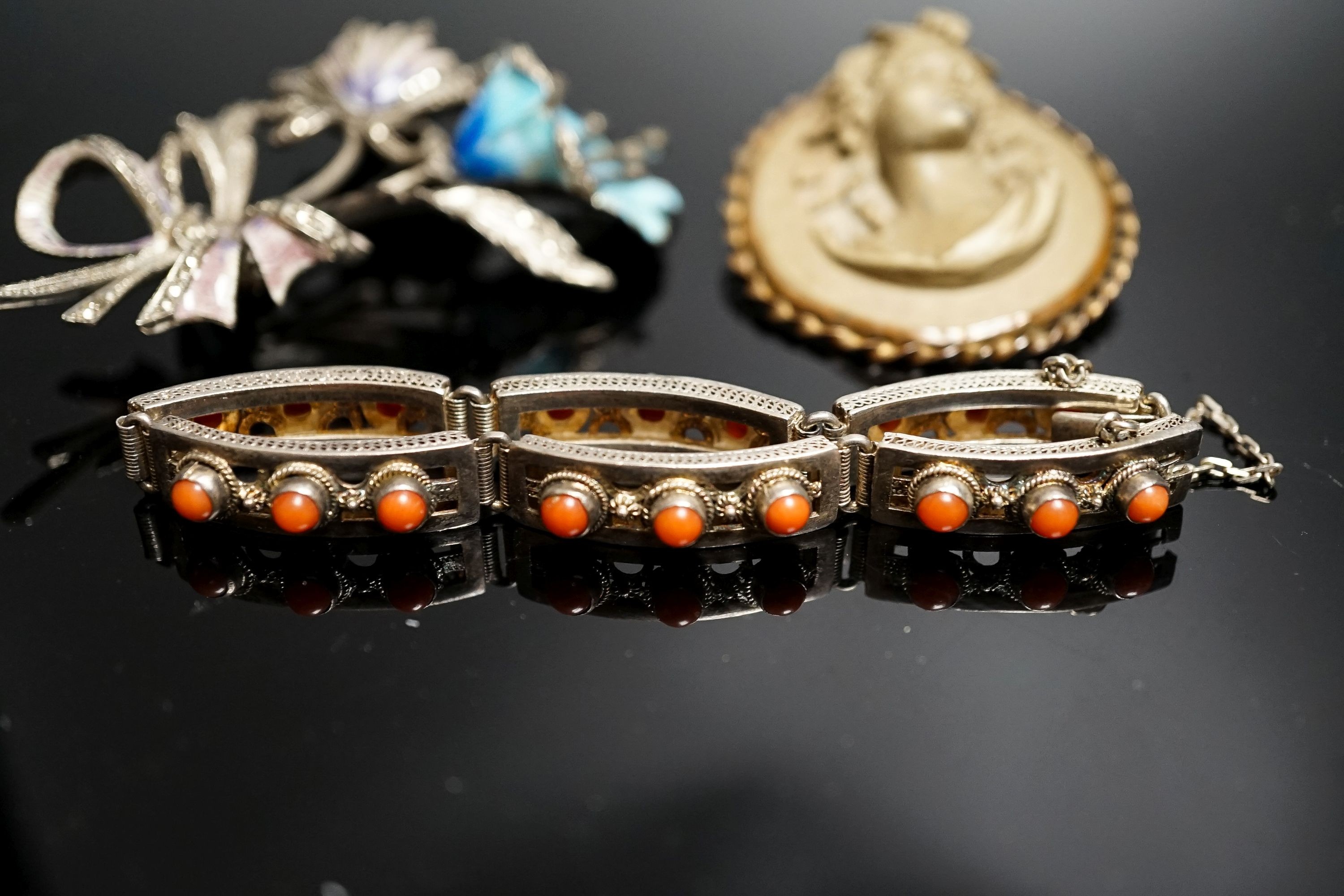 A 19th-century Lava cameo brooch, 49mm, a marcasite and enamel floral spray brooch and a coral mounted white metal bracelet.